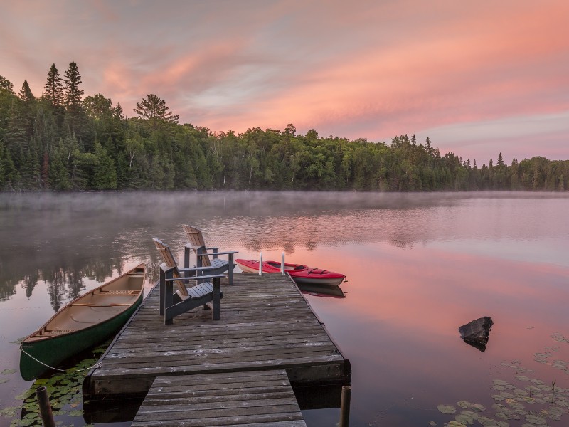 Canoe and kayak moored to a cottage dock at dawn, Muskoka, Ontario