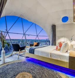 White, spacious bedroom of tent overlooking Texan sunset