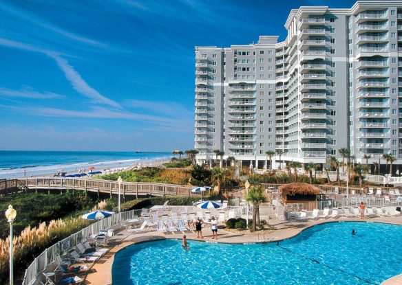 swimming pool by beachfront resort with pier from pool to beach